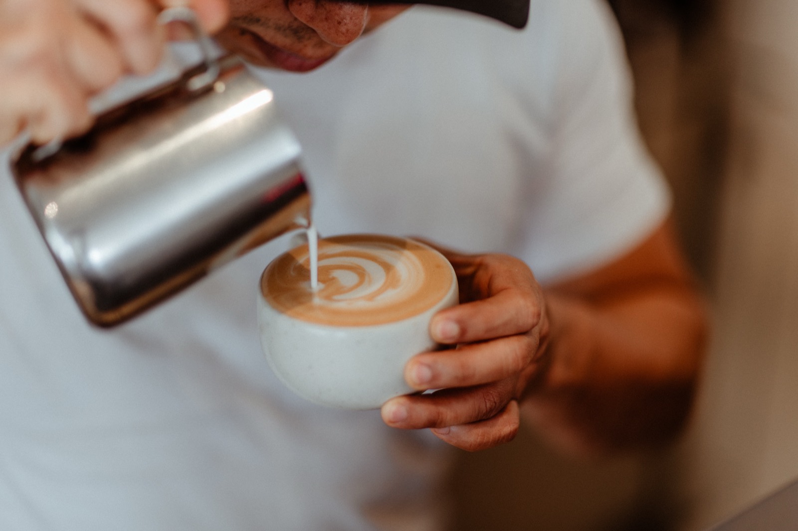 A barista pouring a latte at Amun Café